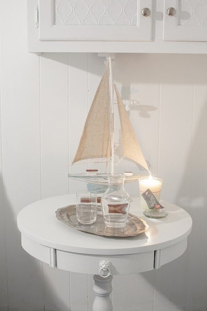 搭配蜡烛，小船小雕像和水玻璃的副桌子上的特写。