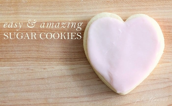一个简单的糖饼干在一个心形的粉红色糖霜，在一个木制的表面。简单和惊人的糖饼干在白色文本覆盖。gydF4y2Ba