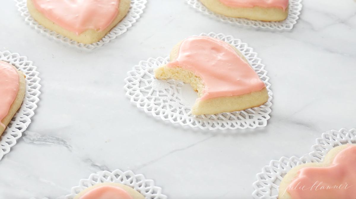 粉红色的心形糖饼干放在大理石表面的心形纸桌巾上。gydF4y2Ba