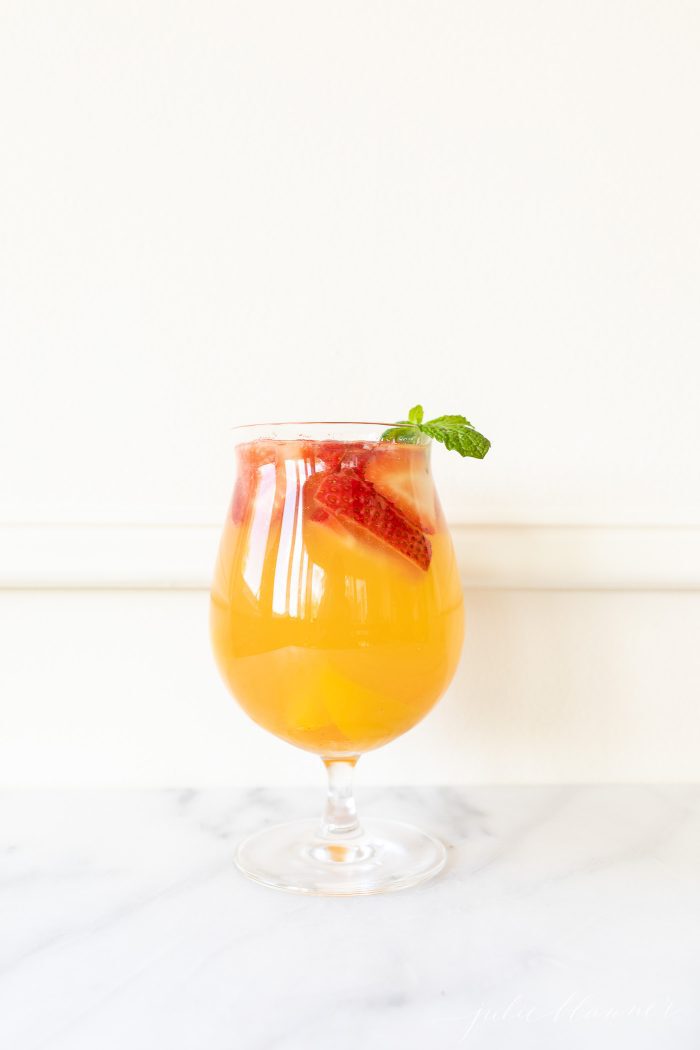 玻璃杯中的桃子桑格利亚汽酒果味桑格利亚太大食谱用薄荷装饰GydF4y2Ba