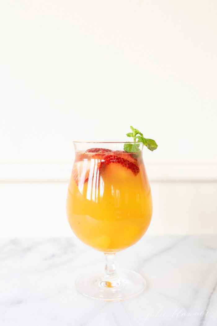 桃子桑格利亚汽酒（Peach Sangria）在玻璃杯中，上面饰有桃子，草莓和薄荷。GydF4y2Ba