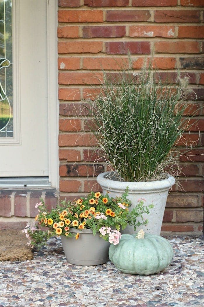 简单的秋季门廊装饰，有草，花和一个南瓜