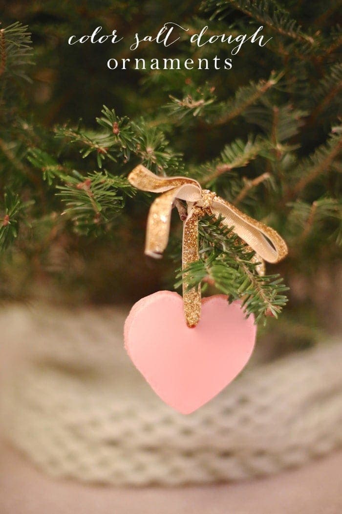 一种粉红色心形的彩盐面团装饰品，挂在圣诞树上的金丝带上。