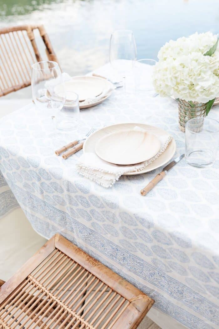 一组在户外餐桌白色的鲜花和一个蓝色和白色的桌布,水在后台。