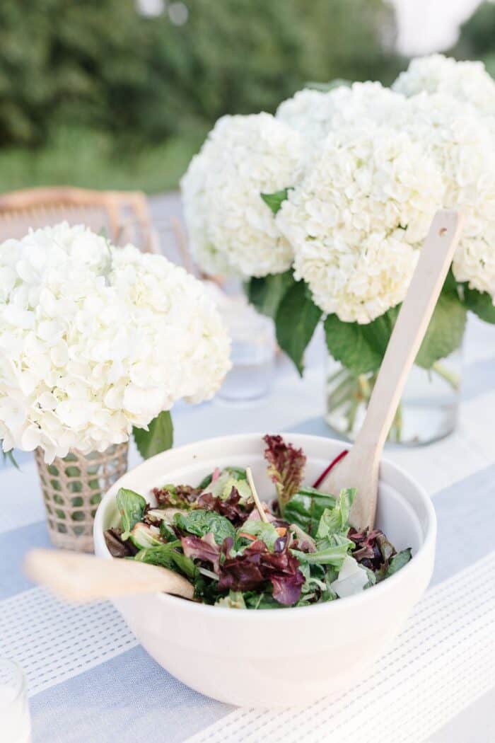 白色绣球花花瓶旁边晚餐沙拉碗设置在户外