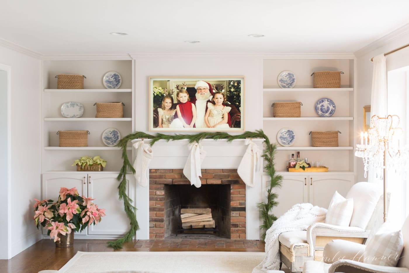 一个白色的客厅，带有白色豪华家居装饰和壁炉上的框架电视。