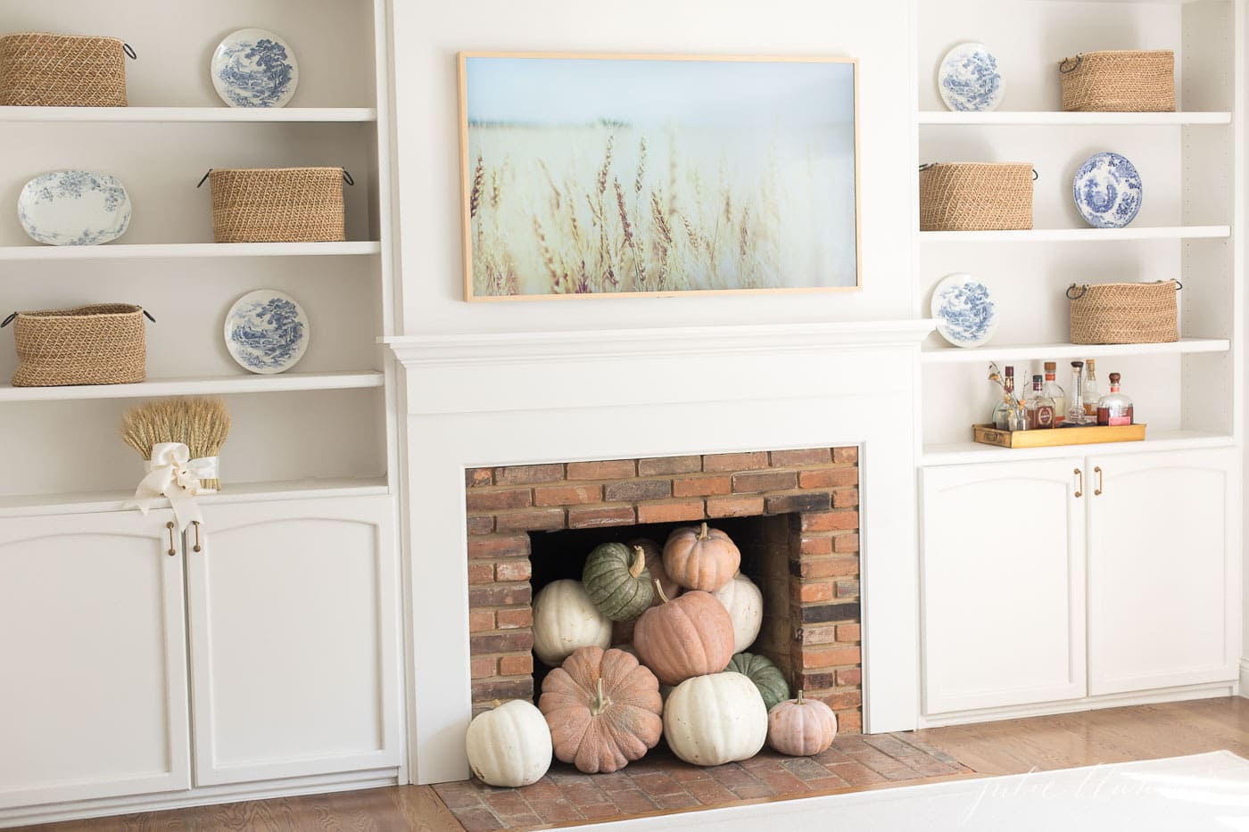 秋季客厅装饰在奶油色的客厅里，有一个砖砌的壁炉和内置的架子