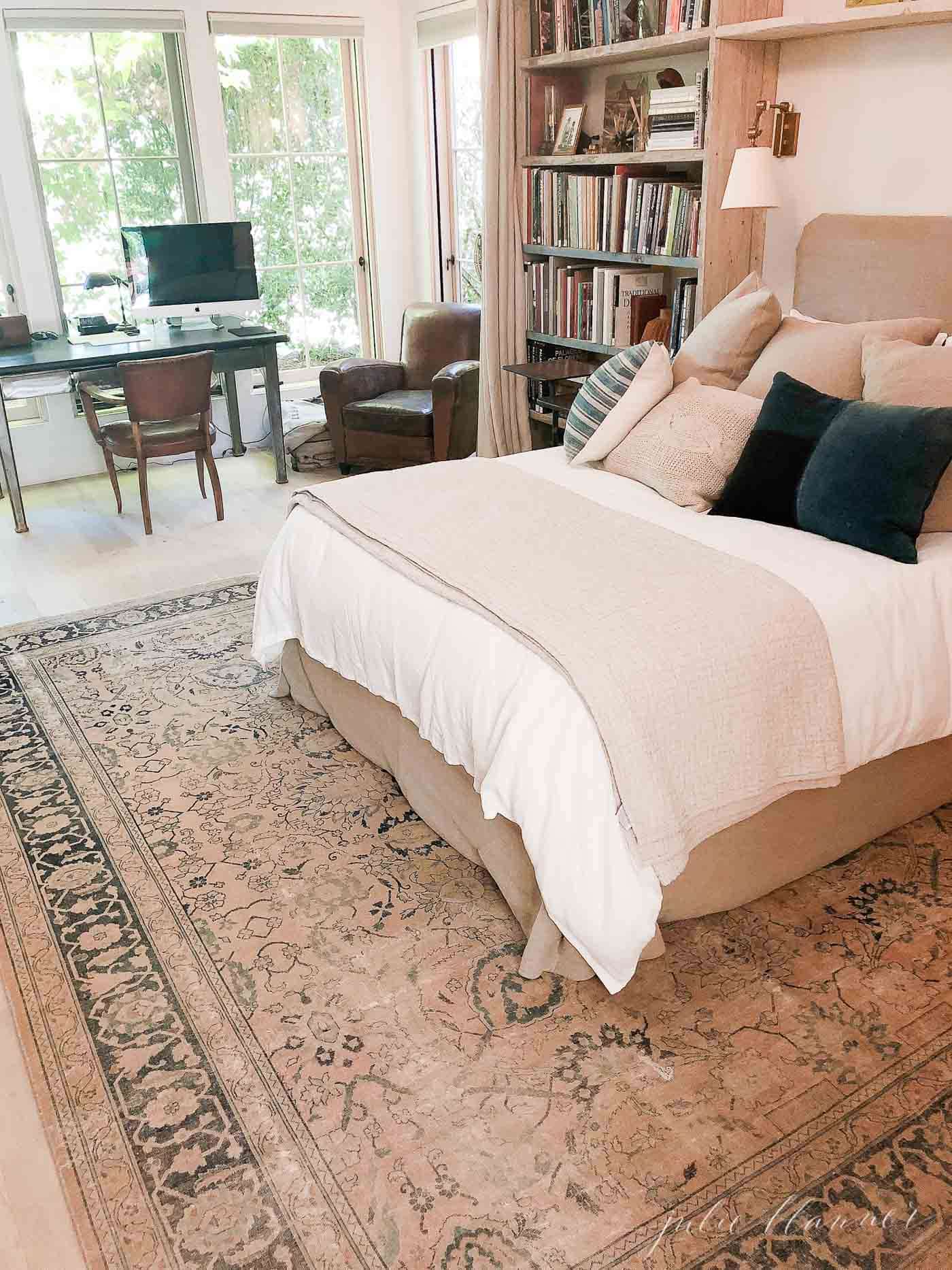 欧式农舍风格的卧室，古董地毯，书架和亚麻床上用品。