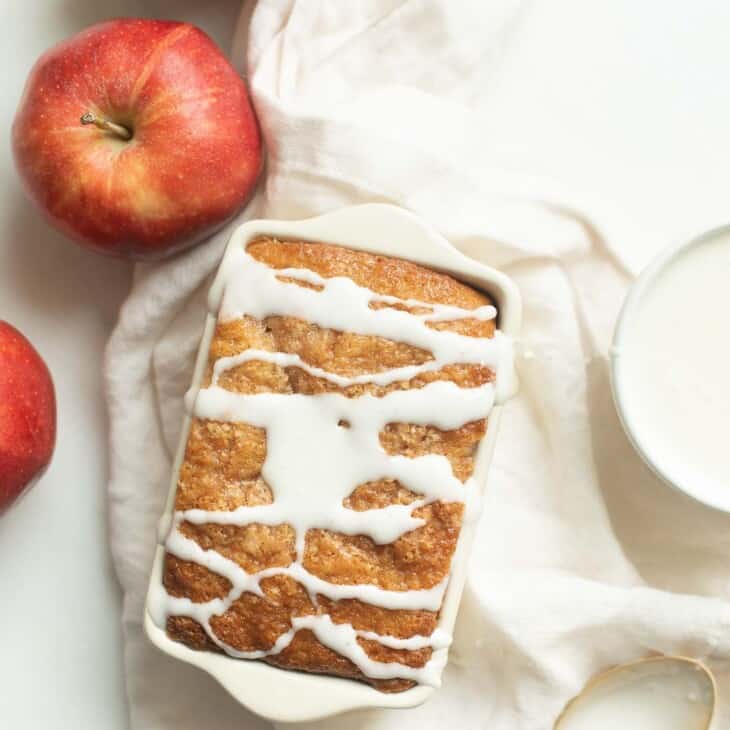 一个白色的表面，苹果和糖霜的一边，与一条苹果面包，釉面淋在上面。gydF4y2Ba