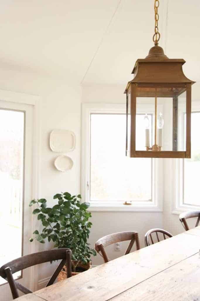 一盏黄铜灯笼挂在一个人物家里的白色餐厅里。