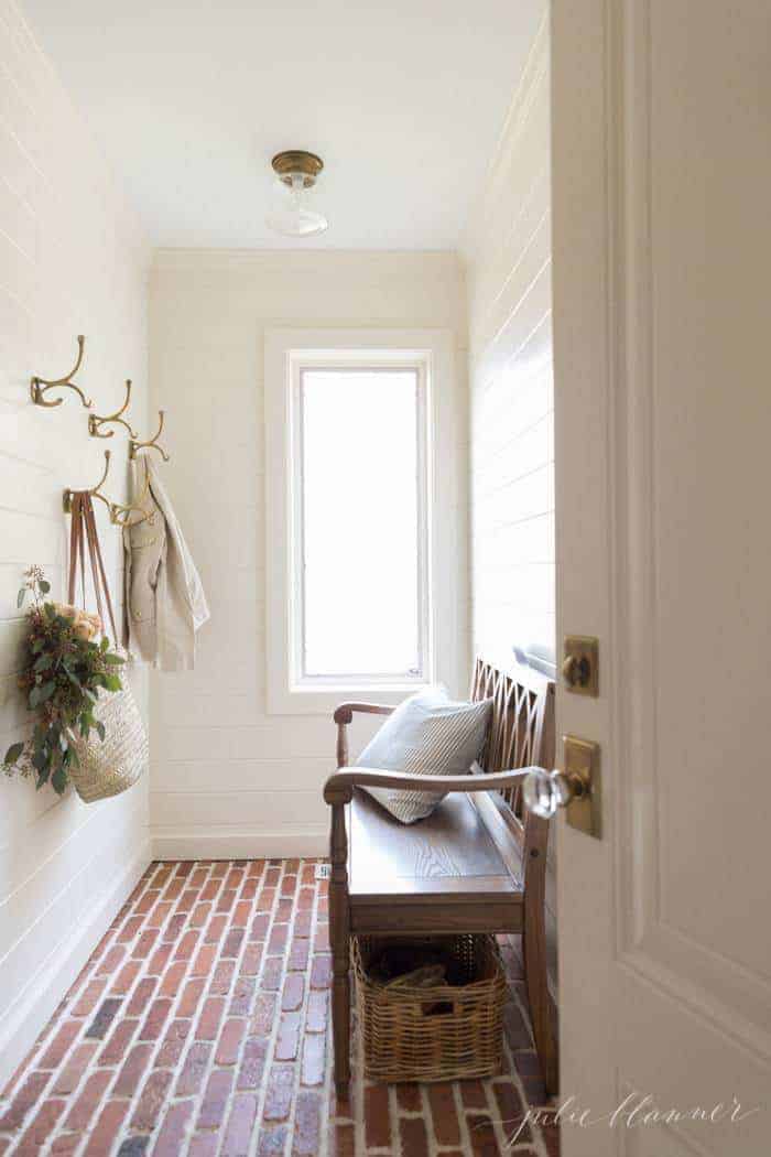 一个带有奶油墙和浅色油漆的泥间，为房间，砖地板增添光。