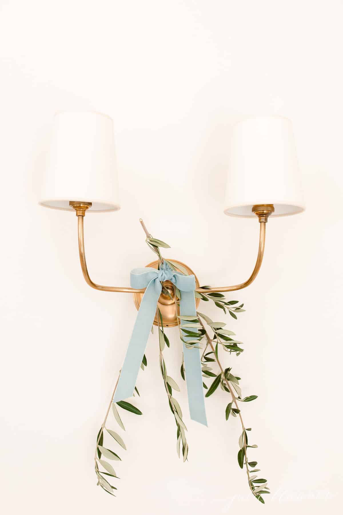 黄铜两个分支墙壁烛台的橄榄枝和蓝丝带系上斯堪的纳维亚圣诞回家之旅。