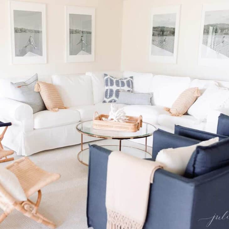 一间现代的白色客厅，墙上挂着大量黑白照片，一套白色组合沙发和海军蓝椅子。