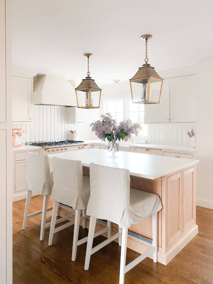 在奶油色的厨房里，黄铜灯笼挂在明亮的木质灶台上，厨房的台面是丹比(Danby)大理石。