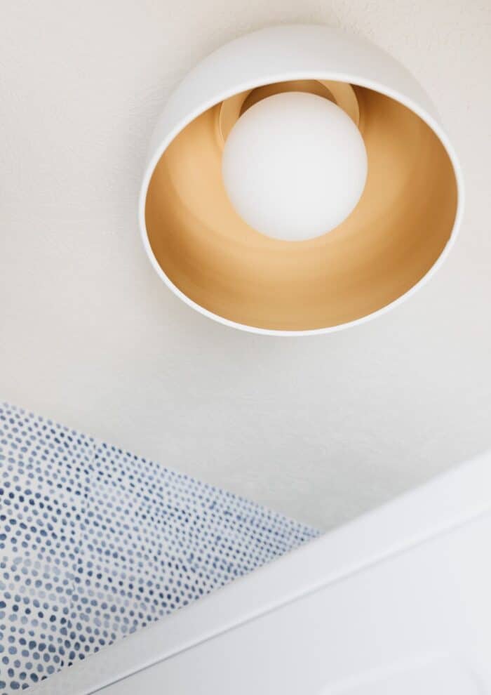 一个现代的金色平齐安装灯具附近的蓝色和白色圆点墙纸。