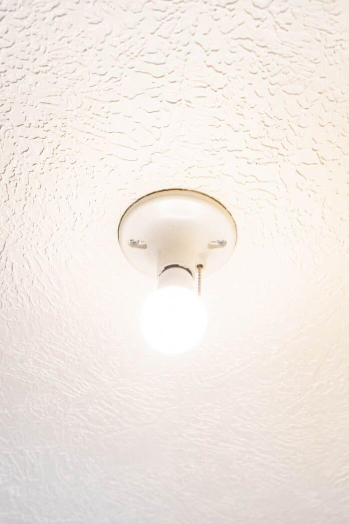 白色天花板上有一个光秃秃的灯泡的拉链式灯具。